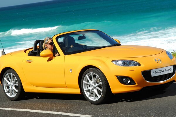 Mazda jaune vif sur fond de vagues de la mer