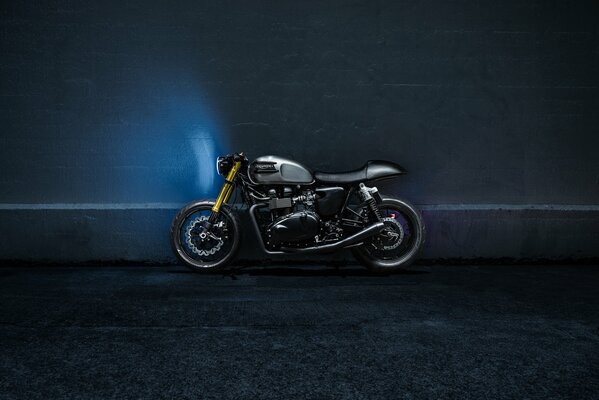 A black motorcycle near a blue wall