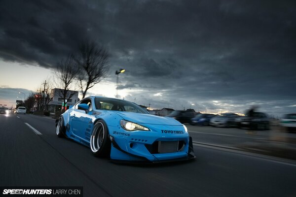 Racing blue toyota under a cloudy sky