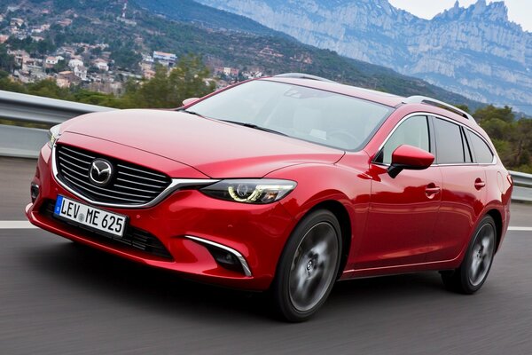 Red Mazda on a beautiful background of mountains