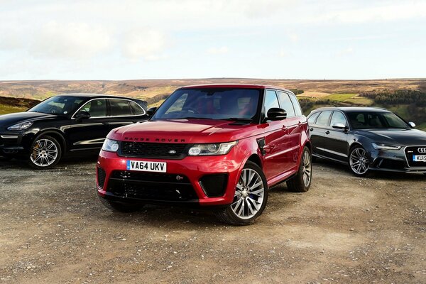 Three cars audi, porsche, land rover, range rover in the field