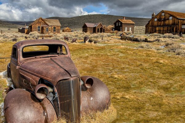 Vieille voiture rouillée sur fond de maisons en bois