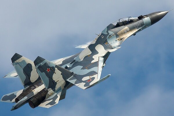 A fighter plane in camouflage is flying