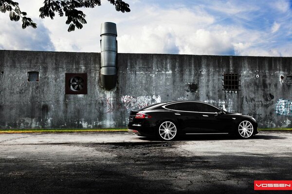 Tesla modelo s negro contra la pared de fondo