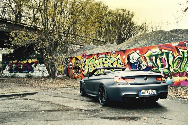 Schwarzes Cabrio und Graffiti an der Wand