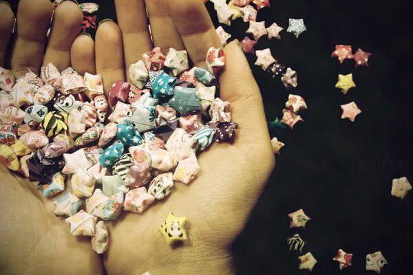 A heart made of candy wrappers in the palms on a dark background