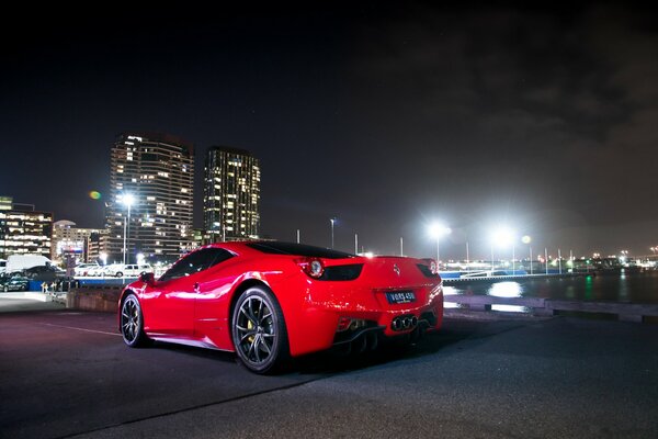 Ferrari rojo en el fondo de la ciudad de la noche