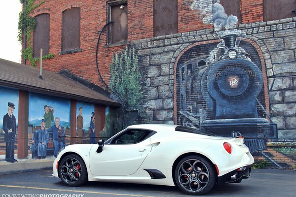 Alfa Romeo bianca contro il muro con il disegno di una locomotiva a vapore