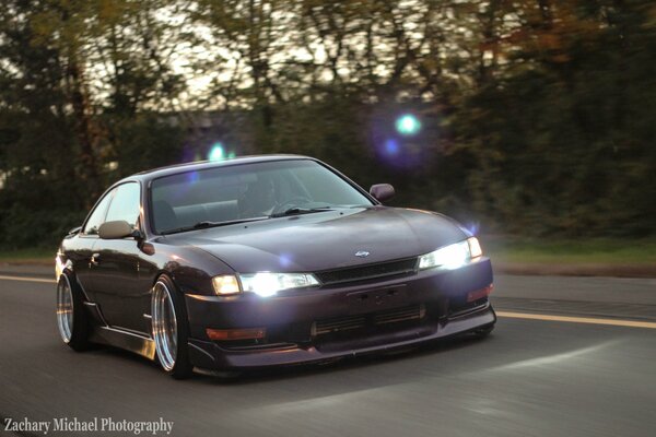 Lila Nissan silvia im Verkehr vor dem Hintergrund von Straße und Wald