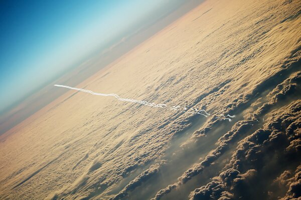 The trace of the plane in the sky against the background of clouds