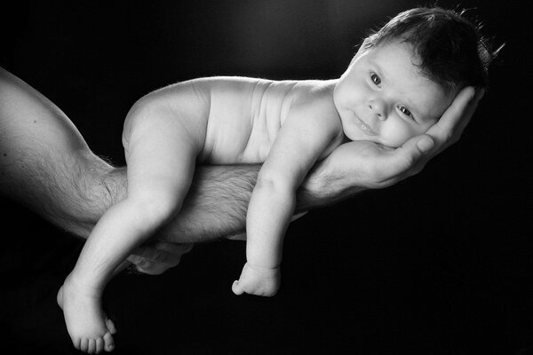 Schwarz-Weiß-Foto eines Babys auf dem Arm eines Mannes