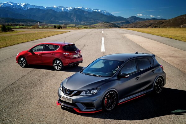 Two cars are standing on the road against the background of mountains