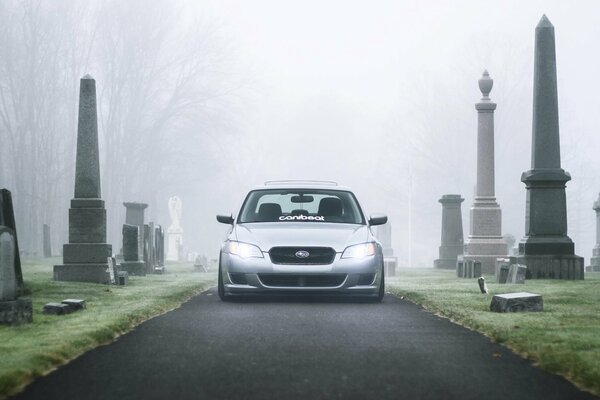 Silberner Subaru auf einem Friedhof im Nebel