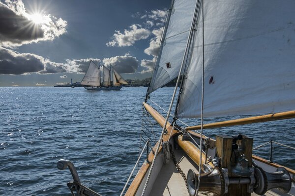 Boats sail around the bay with their sails spread