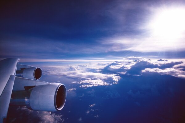 An airplane wing in the air, in the clouds