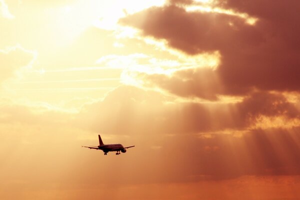 En los rayos del sol, un avión vuela a través de las nubes