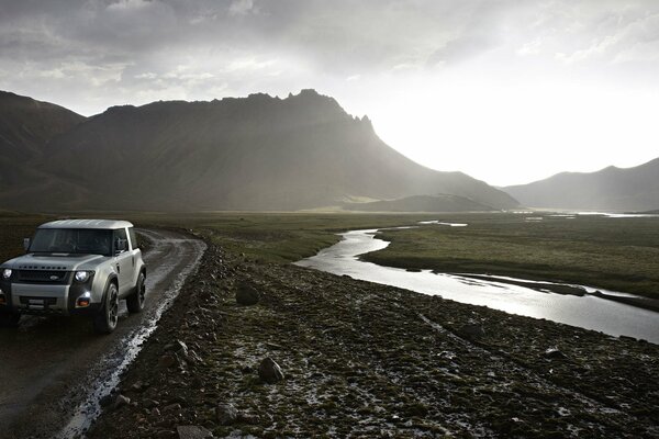 A car on the road against the background of mountains and a stream