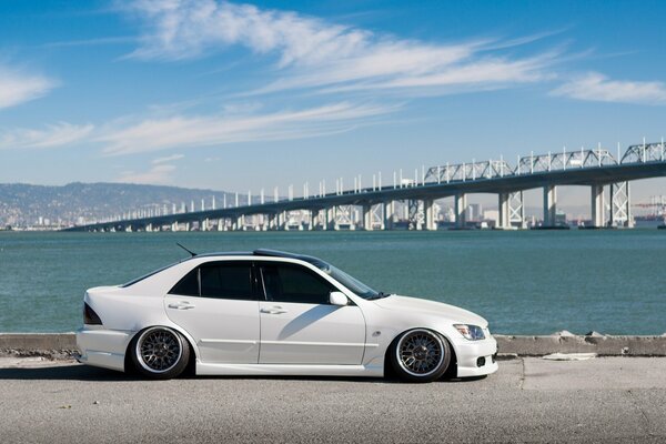 White Lexus on the embankment on the background of the bridge