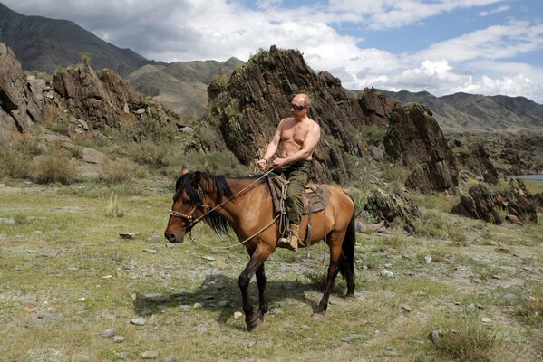 Russian President Vladimir Putin sitting on a horse against the background of mountains