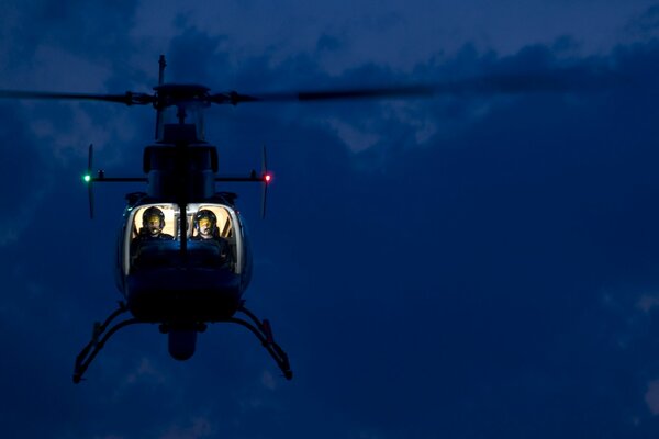 A helicopter with a lighted cockpit hovered in the air