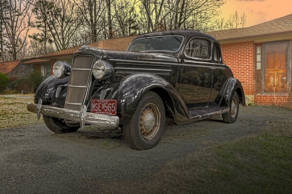 Vintage Dodge coupe car of 1935 on the background of a red brick house