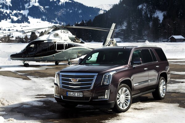 Cadillac und Hubschrauber in einer verschneiten Berglandschaft