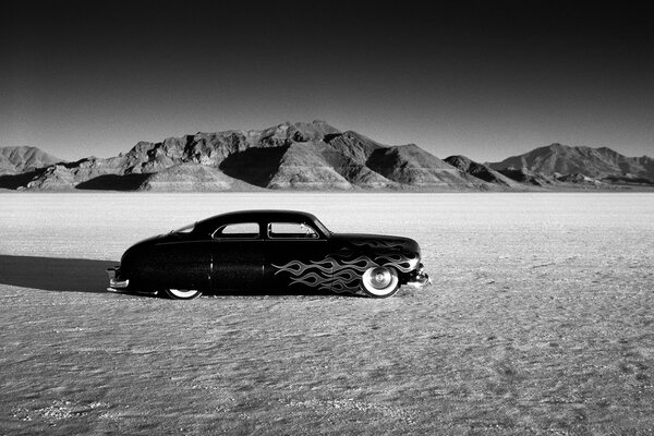 Black and white photo with a racing car on the background of mountains