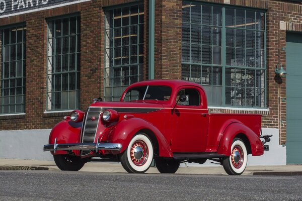 Red retro pickup truck on the background of the building