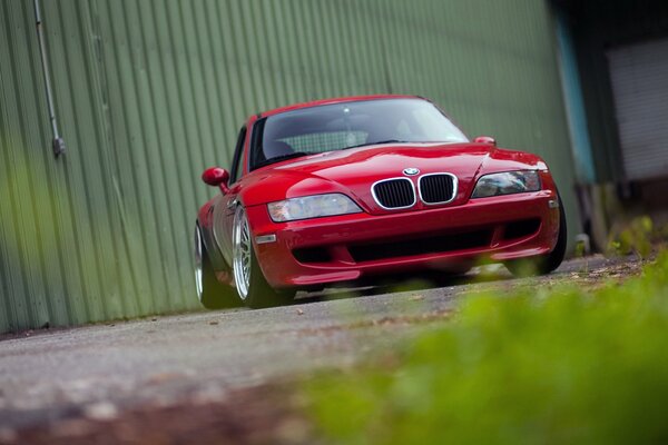 Red BMW view from the front on the background of the fence