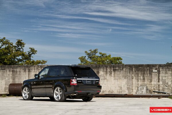 Range rover parcheggiata vicino a una vecchia recinzione e tubi arrugginiti