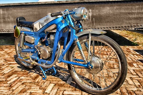 Blue vintage motorcycle on the cobblestone embankment