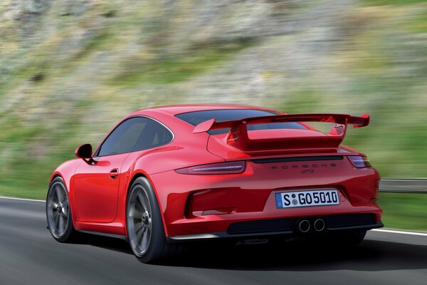 The rear of a red porsche, 911 gt3 with a spoiler at speed