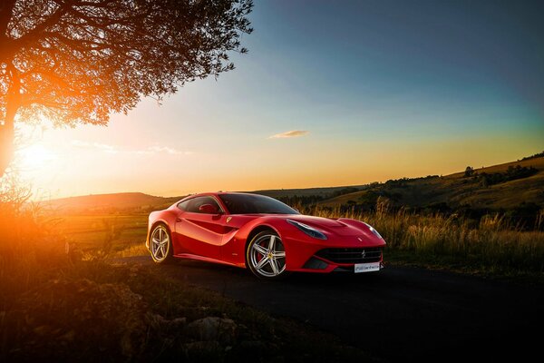 Red Ferrari in the field against the sunset