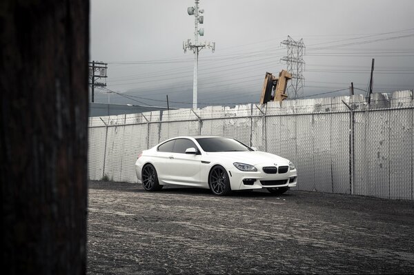 White BMW car on a fence background