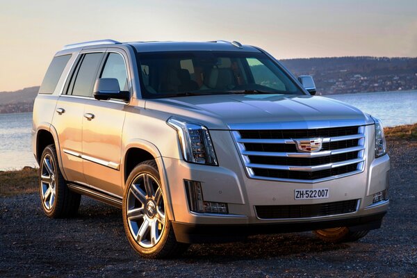 Серебристый cadillac escalade на берегу