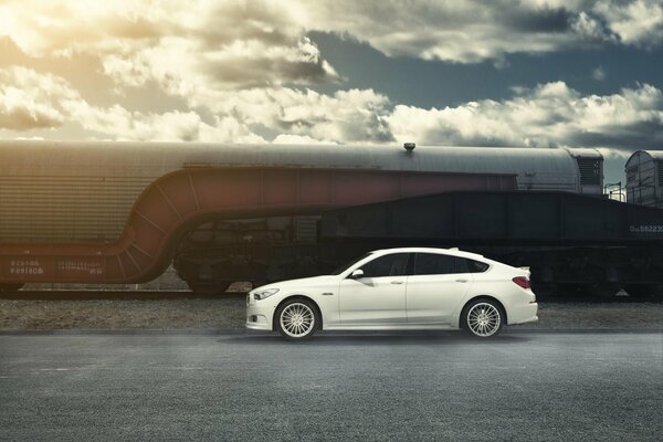 White BMW on the background of railway cars