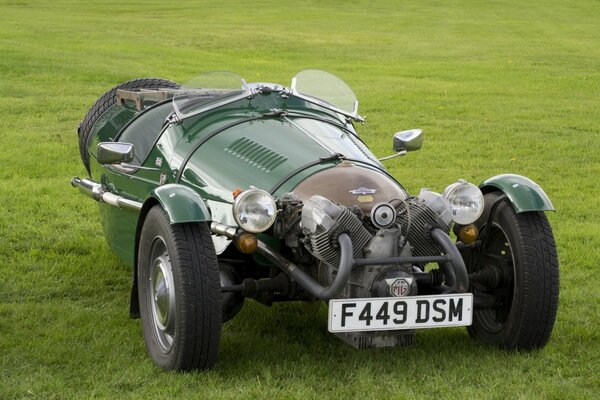 An English car of green color is standing on the grass