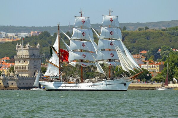 White sailboat on the background of the river and the tower