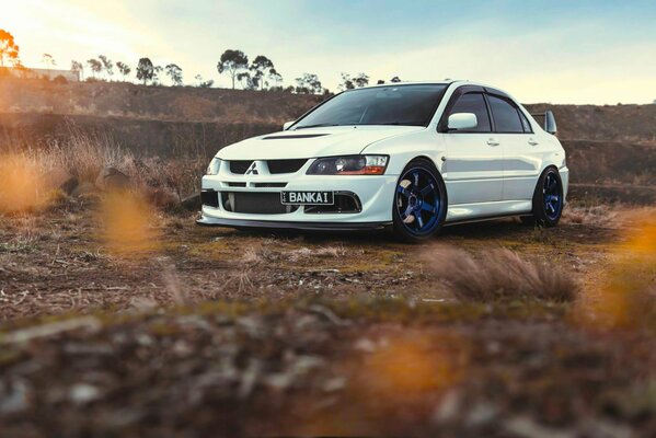 Photo of a white car at sunset. Blue discs