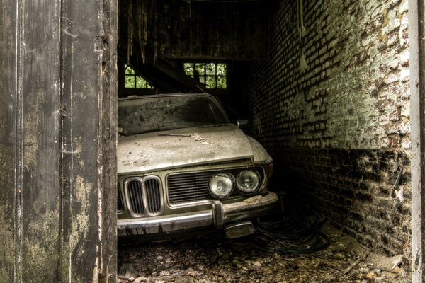 Retro art with an old car forgotten in a brick garage