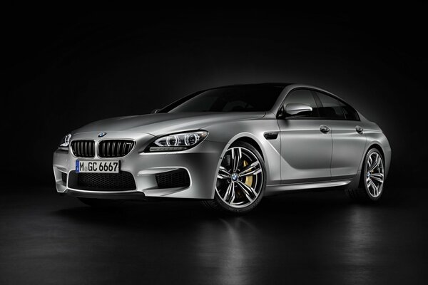 A grey BMW car stands on a black floor