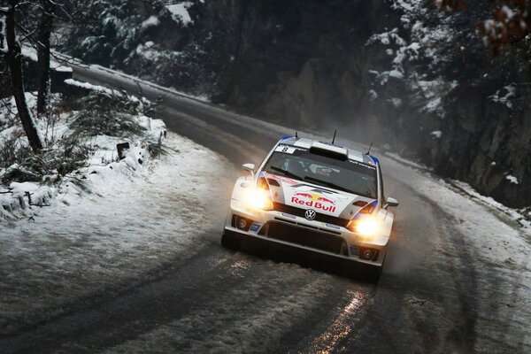 Volkswagen drives along a snow-covered road along the trees