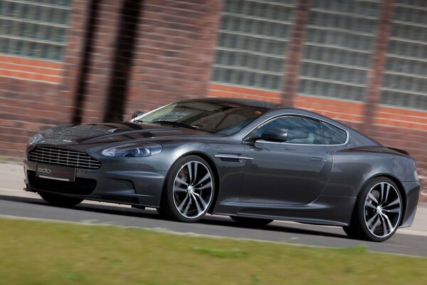 Against the background of a brick building - a black Aston Martin supercar