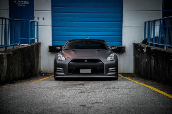 Matte Nissan on the background of blue roller shutters