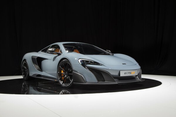 Coche gris McLaren en un círculo negro de Suelo blanco y fondo negro