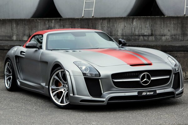 Coche metálico gris con las rayas rojas de Mercedes Benz en el camino cerca de los tanques