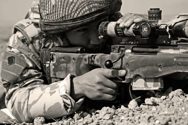 A sniper looking into the sight of a machine gun