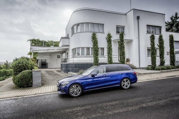 Mercedes-Benz cobalto sullo sfondo di una casa bianca a due piani