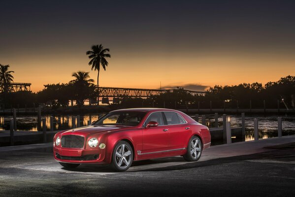 Elegante Bentley rojo sobre fondo de palmeras