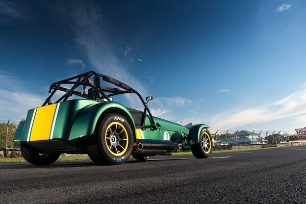 The caterham car is yellow-green against the sky